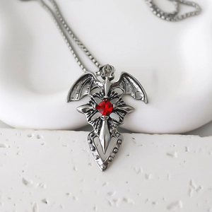 Macro detail of Gothic cross pendant with red gemstone and silver bat wings