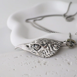 Macro shot of silver eagle head pendant showing intricate feather and beak metal details