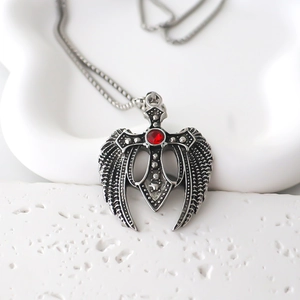 Gros plan du pendentif croix ailes d'ange gothique en acier inoxydable et gemme rouge