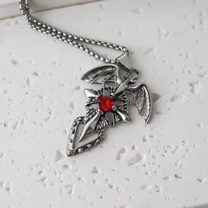 Detailed close-up of gothic cross pendant with red gemstone and silver wings