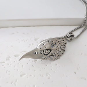 Detailed close-up of a vintage eagle head pendant with intricate feather texture on a box chain