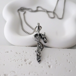 Gothic dragon and sword pendant on a sleek snake chain displayed on a white tray