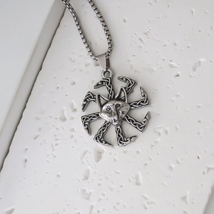 Detail of silver Kolovrat sun wheel pendant with wolf head and Celtic knot textures
