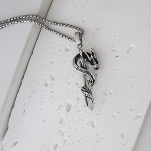 Detailed view of gothic dragon and sword pendant on a textured white stone base