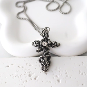 Collier croix gothique avec pendentif serpent et crâne sur fond de pierre blanche