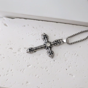 Macro d'un pendentif croix vintage avec relief baroque et zircon blanc sur une chaîne box