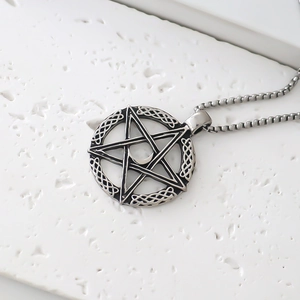 Macro shot of silver pentagram pendant with Celtic knots and moon on a stone plate