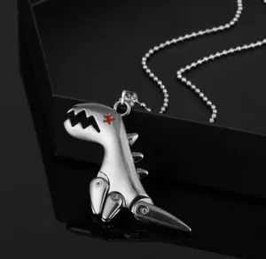 Macro shot of mechanical dinosaur pendant with red star eye and bead chain on black surface