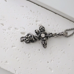 Détail macro du pendentif croix gothique avec crâne et serpent sur fond pierre