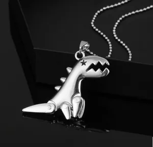 Close-up of silver cartoon dinosaur pendant with star detail and round bead chain