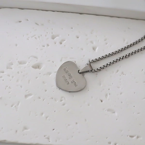 Gros plan du collier avec pendentif coeur argenté et gravure Love you more élégante