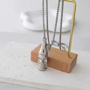 Gothic bottle pendant necklace with skull face on minimalist display stand