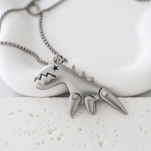 Detailed view of silver dinosaur pendant with star detail on a minimalist white tray