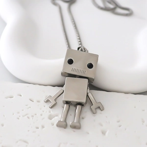 Macro del ciondolo a forma di robot in metallo argentato su un vassoio di ceramica bianca
