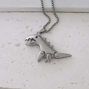 Detail of silver dinosaur pendant with star-shaped eye and matte finish on stone surface