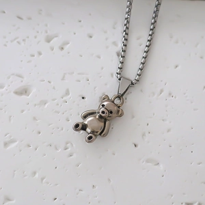 Détail d'un collier chaîne box argenté avec pendentif ours 3D sur pierre blanche