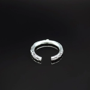 Detail shot of silver open ring featuring vintage floral vine engraving on black background