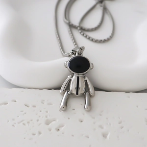 Macro d'un pendentif ours astronaute argenté avec visière noire sur une chaîne fine