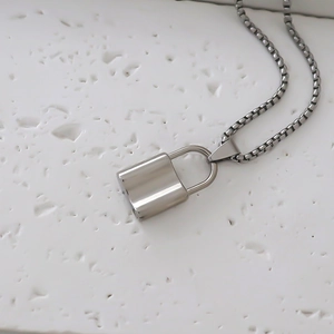 Detail shot of a polished silver padlock pendant on a classic metal box chain necklace