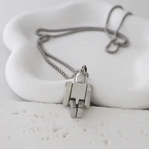 Vue macro d'un pendentif robot géométrique sur une chaîne boîte argentée texturée