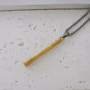 Macro detail of golden staff pendant with cloud carvings on a vintage box chain