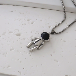 Détail du pendentif astronaute sur texture lunaire avec finitions argentées et noires