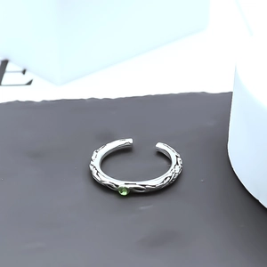Detail of silver adjustable ring featuring vintage engravings and a green gemstone