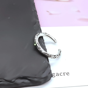 Detailed side view of vintage engraved silver ring featuring a small green gemstone