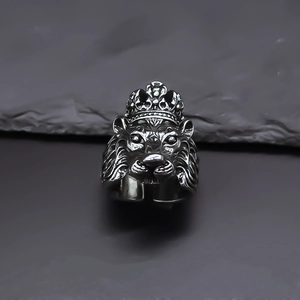 Macro detail of antique silver lion head ring with crown on textured stone background
