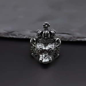 Vintage silver lion head crown ring with cross detail on a dark stone background