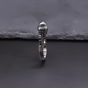 Ethnic Buddha head ring with prayer hands in polished silver finish on a stone surface