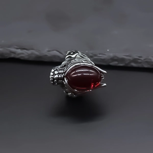 Detailed close-up of a dragon head ring featuring a large oval red gemstone in silver finish