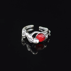 Macro shot of vintage silver punk ring with a red round gemstone and textured finish