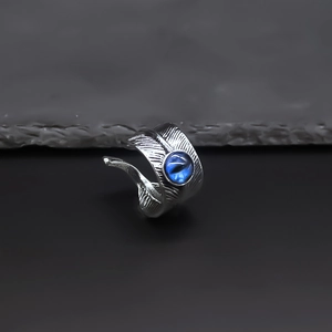 Close-up of retro feather ring with blue cat-eye stone on dark rock texture surface