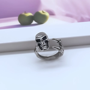 Close-up of retro silver skull and claw open ring on a white geometric platform