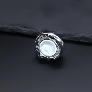 Macro detail of silver evil eye ring with irregular lava texture and polished white inlay