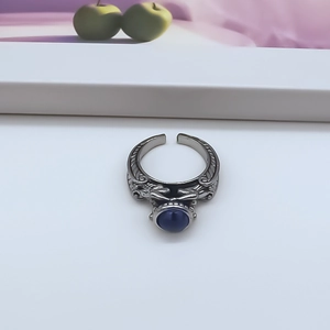 Detail of vintage adjustable alloy ring with blue cat eye stone and engraved wave patterns