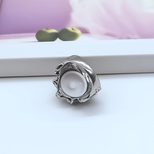 Macro shot of silver ring with irregular lava texture and central white enamel circular inlay