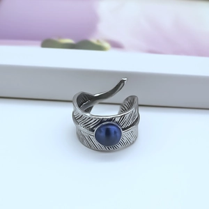 Detail of vintage silver feather ring with a central blue bead on a white stand