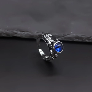 Retro punk adjustable dragon ring with blue crystal eye on grey rock surface