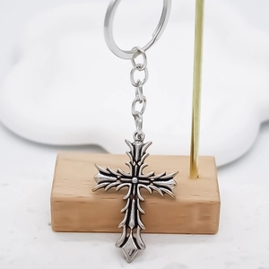 Close-up of gothic silver cross keychain with antique finish on a display stand