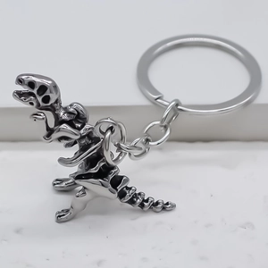 Porte-clés rétro en métal argenté avec squelette de dinosaure T-Rex sur fond blanc