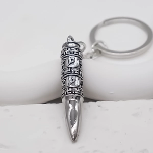 Vue macro du porte-clés pendentif balle en argent avec gravure religieuse et anneau