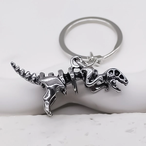 Détail d'un pendentif squelette de dinosaure argenté sur un anneau porte-clés en métal