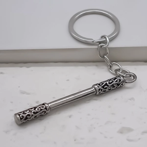 Retro silver metal keychain with Ruyi Jingu Bang staff pendant on white stone surface