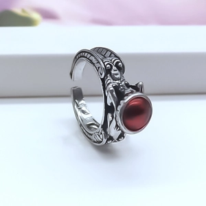 Close-up of vintage silver alloy ring featuring a large matte red stone with gothic relief