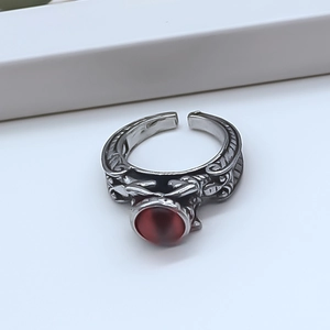 Macro shot of retro silver alloy ring featuring ornate texture and a red cat-eye stone