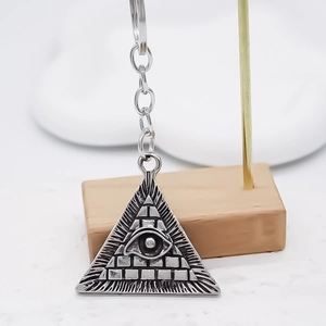 Gros plan du pendentif œil du démon en métal argenté avec des détails de pyramide