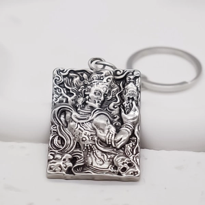 Macro view of rectangular silver alloy keychain with vintage Buddhist relief carvings
