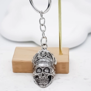 Retro silver metal skull keychain with officer hat hanging on a professional stand